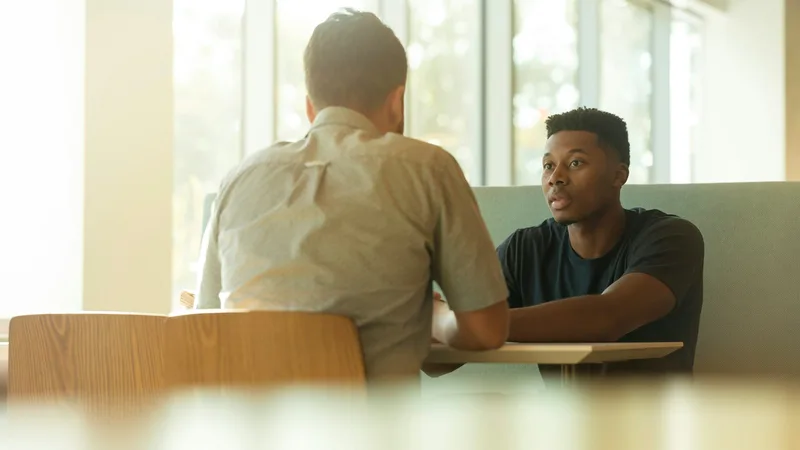 Two colleagues in conversation at a table by a window