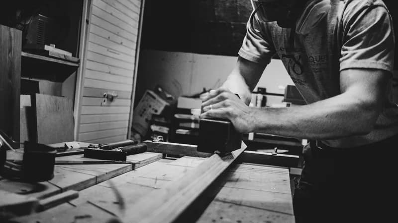 An instructor guiding an apprentice at a joinery bench