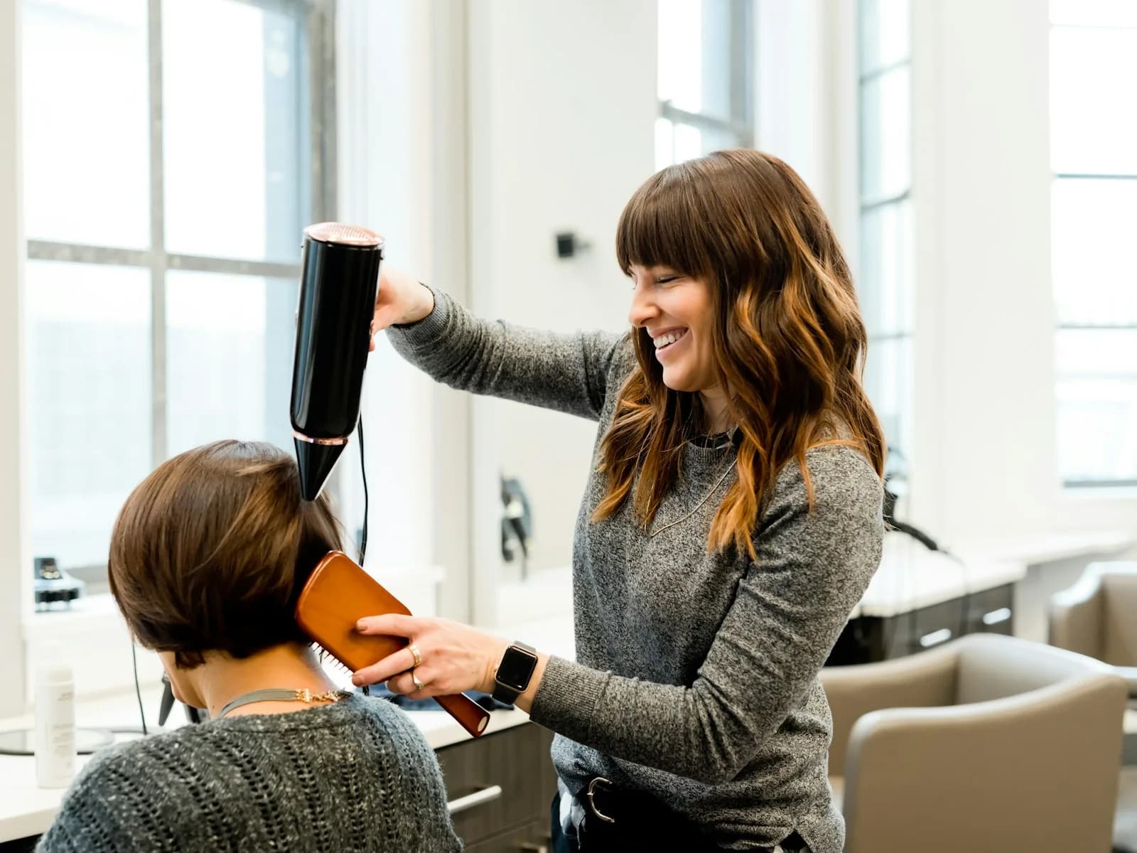 A hairdressing tutor styling hair in a training salon