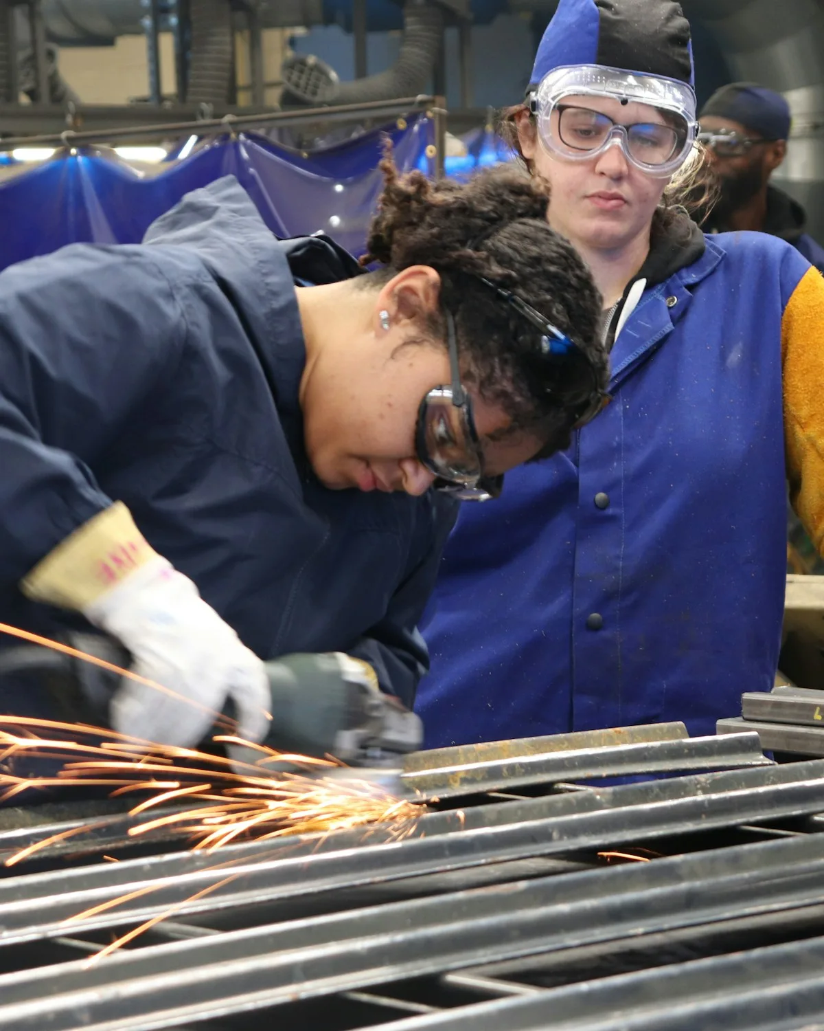 Welding students working with their tutor in a college workshop