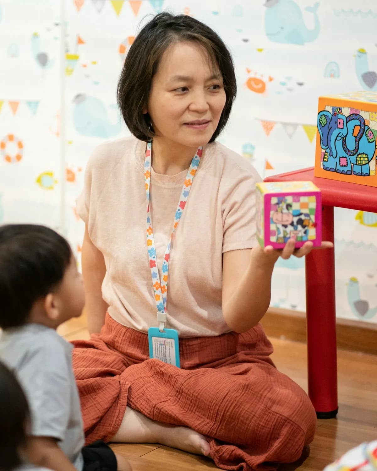 An early years practitioner showing a picture card to young children