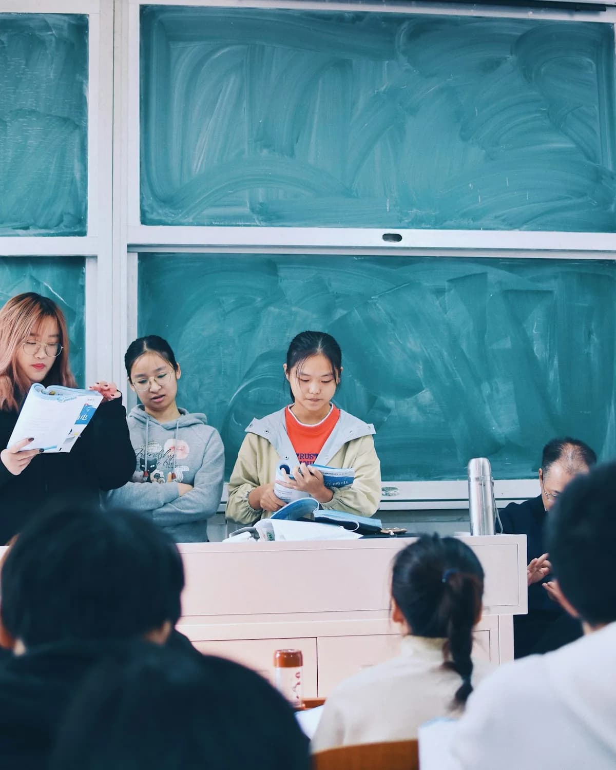 Students reading aloud at the front of a classroom