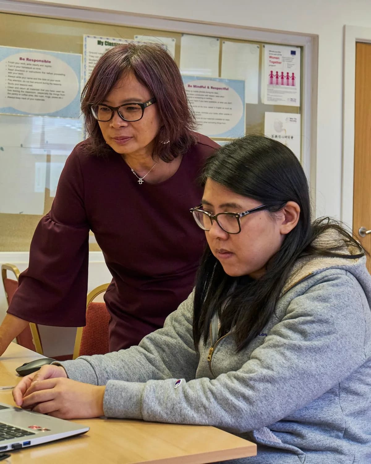 A mentor going through work with a trainee teacher at a laptop